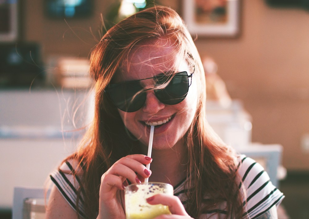 Joven con gafas de sol disfrutando una bebida fría