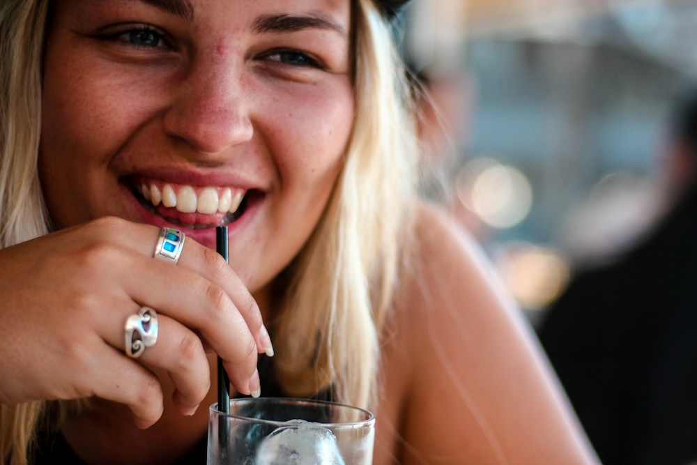 Mujer sonriendo mientras toma una bebida con pitillo